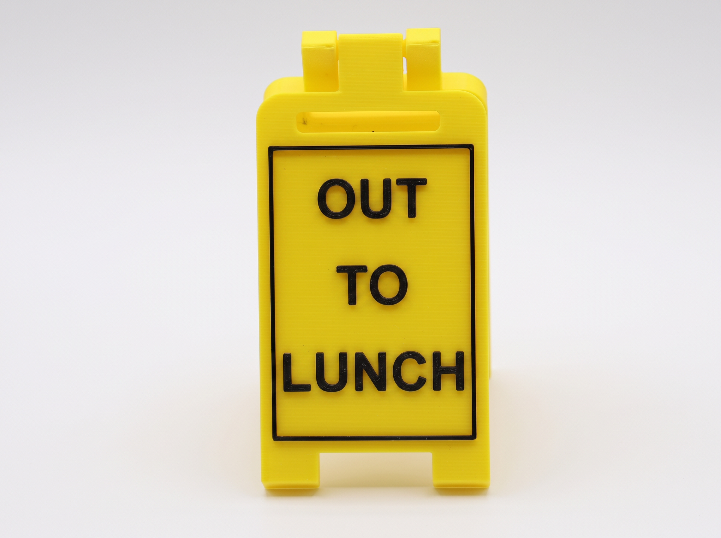 'Out to Lunch' yellow fold-out desk sign with raised black lettering